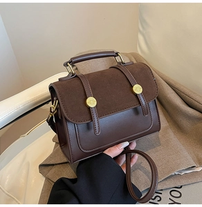 Detail of dark brown crossbody bag with gold buckle and smooth leather-suede texture
