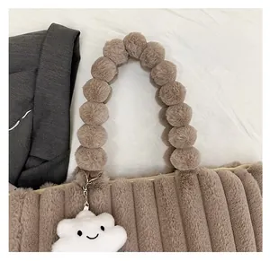 Detail of plush tote bag showing vertical texture and unique pom-pom ball handle