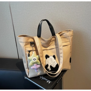 Dettaglio della borsa tote in tela beige con patch panda e portachiavi a stella
