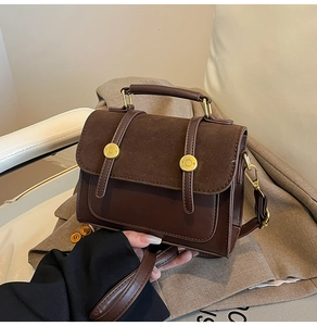 Detail of vintage brown leather crossbody bag with gold hardware and top handle grip