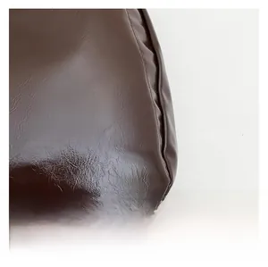 Gros plan d'un cabas en cuir verni marron chocolat avec détails plissés brillants
