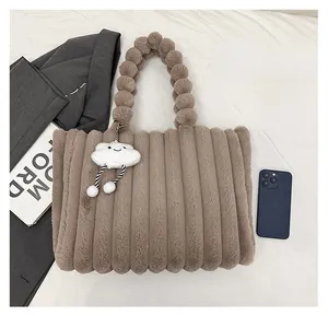 Brown plush tote bag with striped texture and fuzzy ball handle shown beside a phone