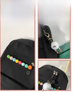 Close-up of black backpack featuring colorful pom-poms and a cute plush monster charm