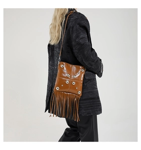 Dettaglio borsa in pelle marrone vintage con borchie argentate, frange e cuciture a croce