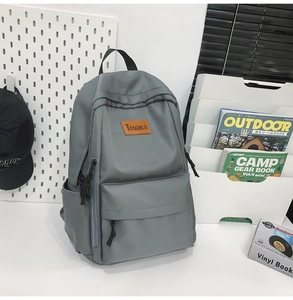 Close-up of durable gray nylon backpack with brown leather logo patch for students