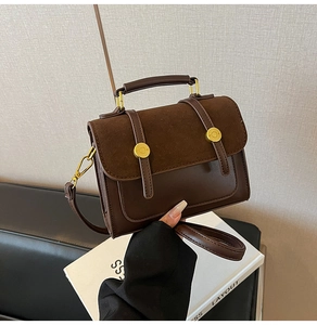 Detail of vintage brown leather crossbody bag featuring gold metal lock and suede texture