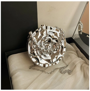 Detailed view of silver rose shaped hard shell evening bag on silk lining with chain strap