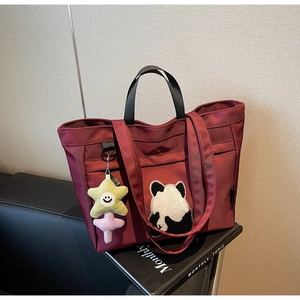 Dettaglio borsa shopper bordeaux con toppa panda e ciondolo stella gialla su divano nero
