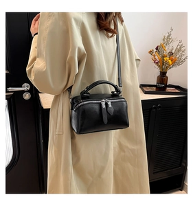 Detail of minimalist black leather Boston bag with zipper and detachable shoulder strap