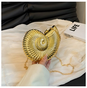 Detail of golden nautilus shell evening bag with metallic finish and delicate chain strap