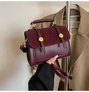 Close-up of wine red crossbody bag featuring suede flap texture and gold metal buckle
