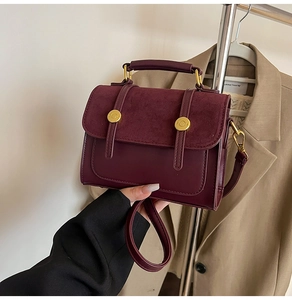Detail of burgundy leather crossbody bag with gold buckle and suede texture contrast