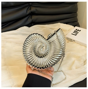 Detailed macro view of silver snail shell evening clutch with polished spiral metallic texture