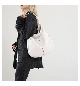 Détail d'un sac cabas blanc crème brillant avec rivets métalliques porté par un mannequin