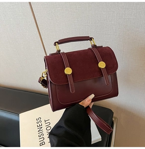 Detailed macro view of burgundy vintage crossbody bag with mixed leather and suede texture
