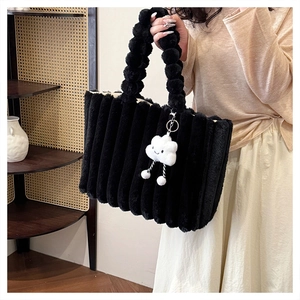 Detail of black faux fur tote bag with vertical stripes and cloud plush pendant