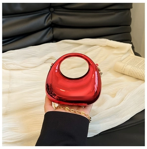 Detalle de bolso de acrílico rojo con acabado de espejo y correa de cadena dorada