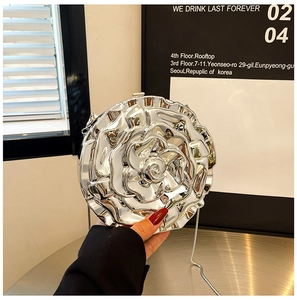 Detail of silver metallic rose-shaped handbag with reflective 3D floral texture and chain