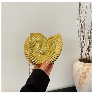 Close-up of golden snail shell evening bag with metallic finish and chain strap