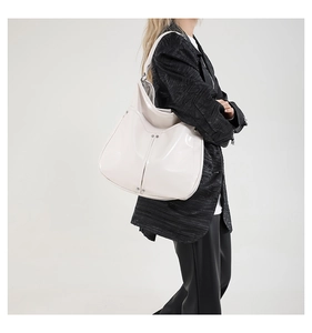 Gros plan du sac hobo en cuir verni blanc crème avec clous argentés sur un mannequin