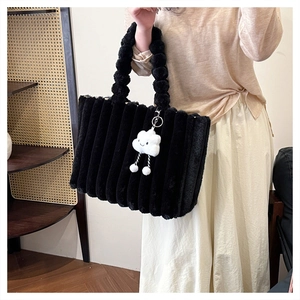 Detail of black faux fur tote bag featuring vertical stripe texture and unique ball handles