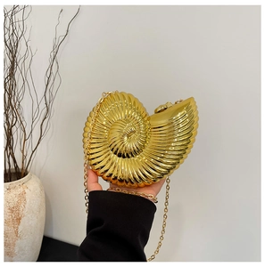 Close-up of golden snail shell evening bag with shiny metallic finish and chain strap