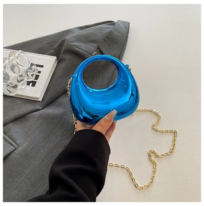 Detalle de bolso de acrílico azul metalizado con correa de cadena dorada