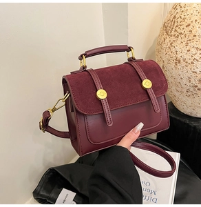 Detail of vintage burgundy crossbody bag showing textured leather and gold hardware