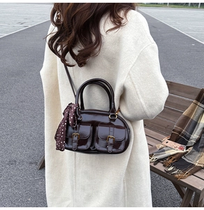 Detail of dark brown boston bag with twin front pockets and a polka dot silk scarf