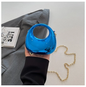 Detalle de bolso de acrílico azul metálico efecto espejo con cadena dorada
