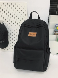 Minimalist black backpack with leather label shown against a modern white studio background