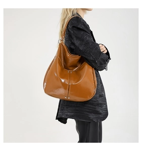 Détail du sac cabas en cuir verni marron caramel avec rivets et anneaux argentés