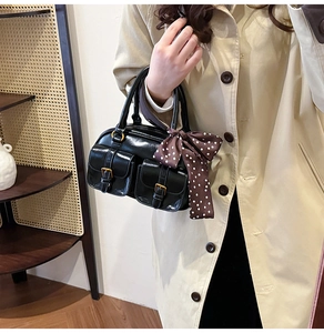 Detail of a vintage black Boston bowling bag featuring gold buckles and a polka dot scarf