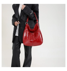 Détail du sac hobo en cuir verni rouge avec anneau métallique et rivets décoratifs