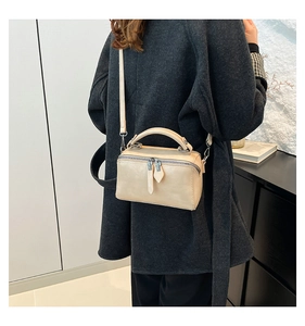 Detail view of cream bucket bag showing silver hardware and smooth matte leather texture