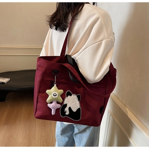 Dettaglio della borsa tote in tela bordeaux con ricamo panda e ciondolo a stella