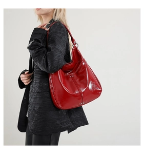 Détail du sac cabas en cuir verni rouge avec rivets argentés et large bandoulière