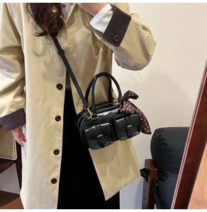 Close-up of black glossy leather bowling bag with polka dot scarf and gold hardware