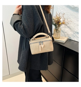 Detailed view of beige Boston bag worn as a shoulder bag with adjustable strap