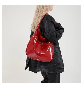 Grand sac cabas en cuir verni rouge porté par un mannequin avec détails argentés
