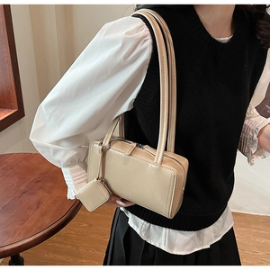 Dettaglio della borsa a spalla beige rettangolare con spalline sottili e mini borsellino