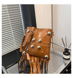 Dettaglio della borsa in pelle marrone con borchie argentate e lunghe nappe