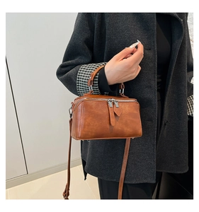 Detail of vintage brown rectangular bucket bag with double zip and leather texture
