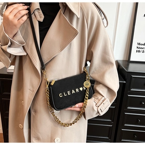 Detail of black matte crossbody bag with golden chain and CLEAR logo on a luxury interior