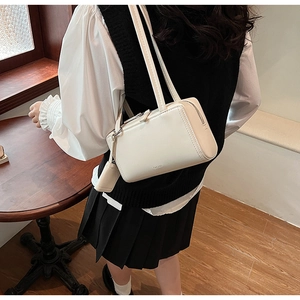 Dettaglio borsa a spalla in pelle bianco crema con cuciture sottili e zip metallica