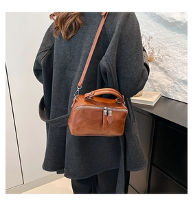 Rear view of a model carrying a brown minimalist bucket bag with polished leather finish