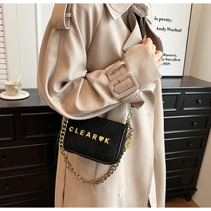 Detail of matte black crossbody bag with gold chain strap and metallic logo lettering