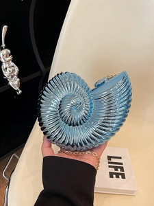 Deep blue snail-shaped acrylic evening bag with gold chain strap in hand display
