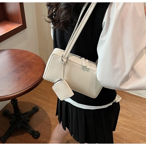 Modella che indossa una borsa a spalla crema rettangolare con mini astuccio appeso