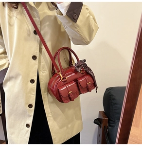 Detail of a dark red mini bowling bag with shiny leather finish and polka dot silk scarf